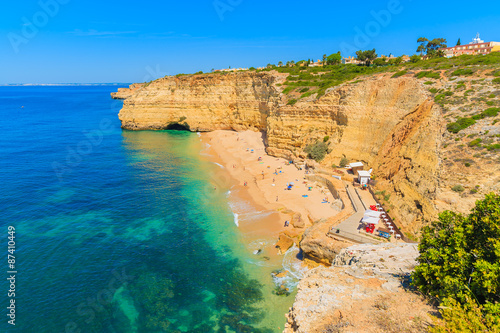 View of beach with golden color cliff rocks near Carvoeiro town, Algarve region, Portugal