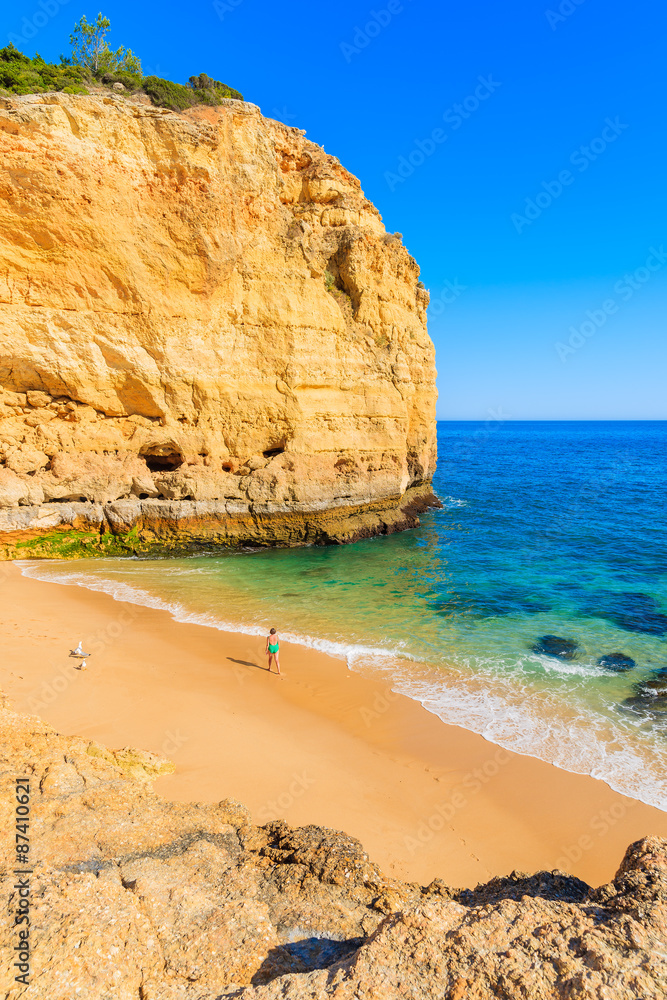 Fototapeta premium Unidentified woman walking on sandy beautiful Val Centianes beach, Algarve region, Portugal