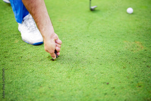 Fotografi Golf player repairing divot