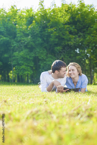 Young Caucasian Couple in love Outdoors Lying on Grass and Havin
