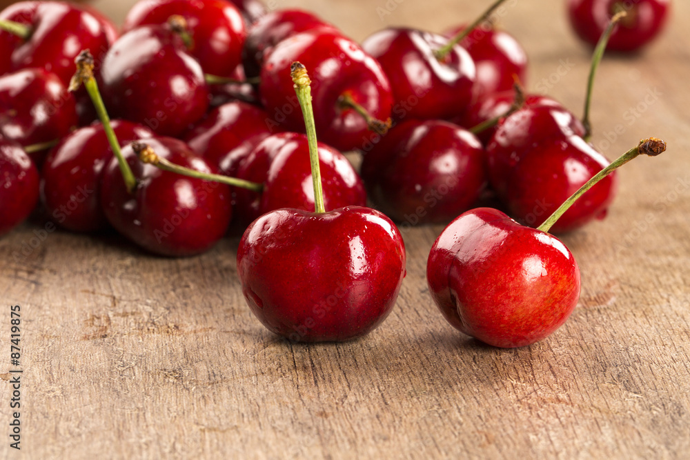 A wooden pot full of cherries over a wooden surface A wooden pot full of cherries over a wooden surface