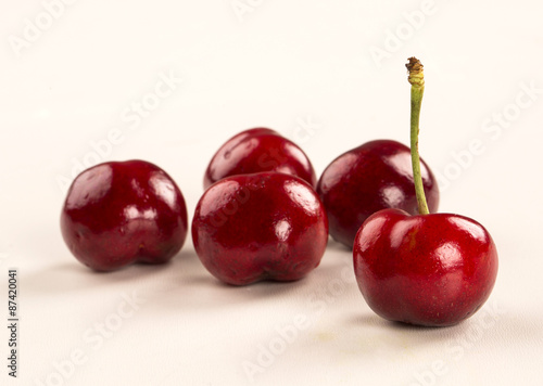 A wooden pot full of cherries over a wooden surface