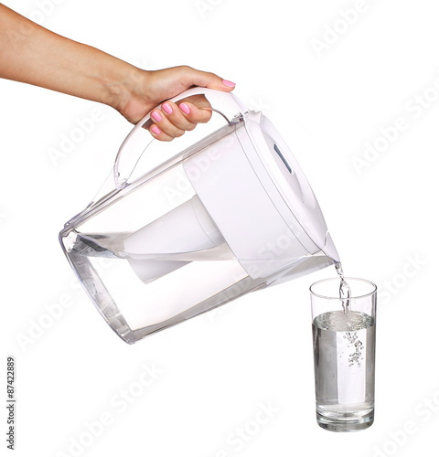 hand holding water filter jug and pouring water into a glass iso