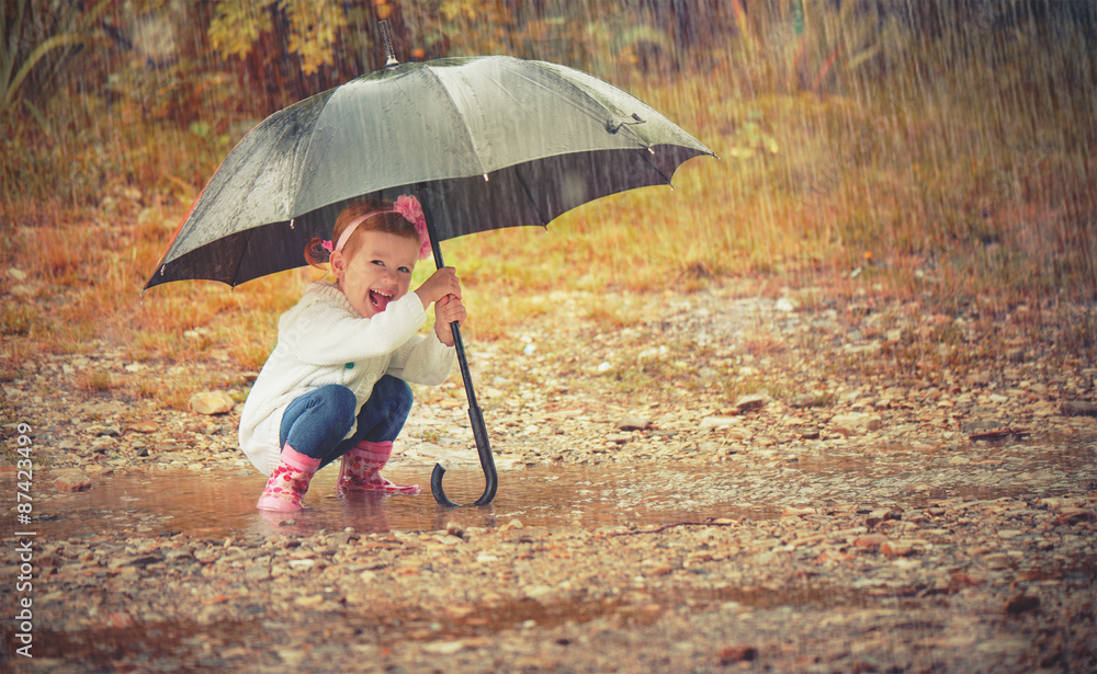 happy baby girl with an umbrella in the rain playing on nature Stock Photo  | Adobe Stock