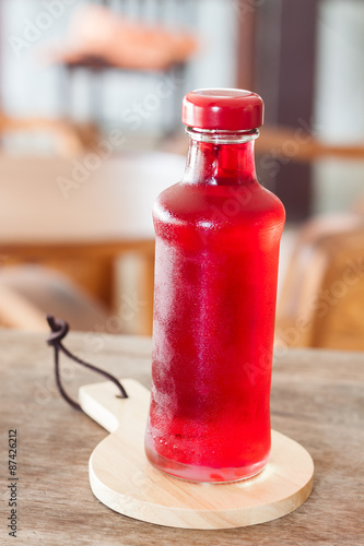 Red syrup in the bottle on wooden plate