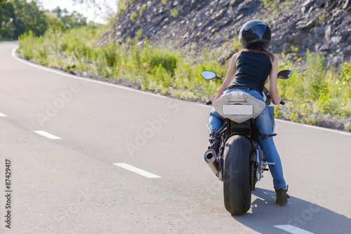 Blonde girl rides on modern motorcycle.