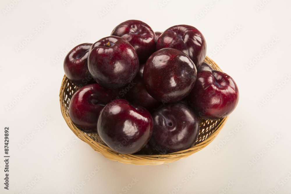 Fresh bright plums in the bowl on board Fresh bright plums in the bowl on board