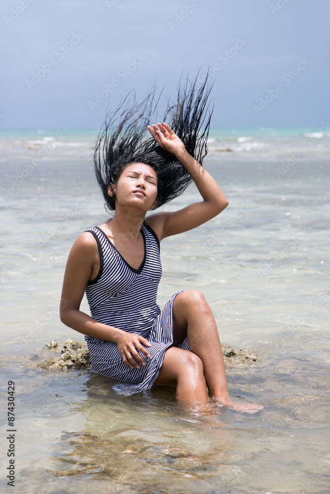 Naklejka premium woman sitting in the sea and playful with her hair 
