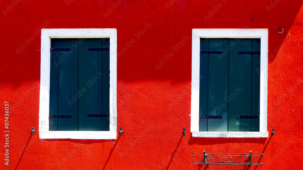 two windows with white frame on red color wall