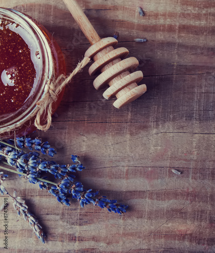 Honey in a glass jar, honey spoon and lavendre flowers on the wo photo