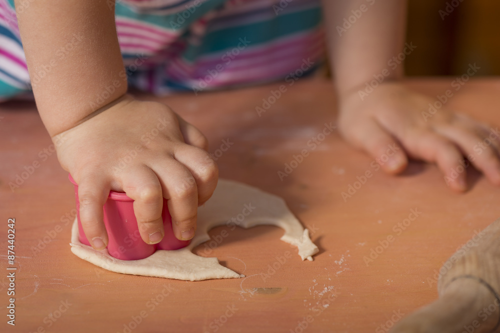Little chef hands smeary with flour cutting the dough in flower shaped Little chef hands smeary with flour cutting the dough in flower shaped