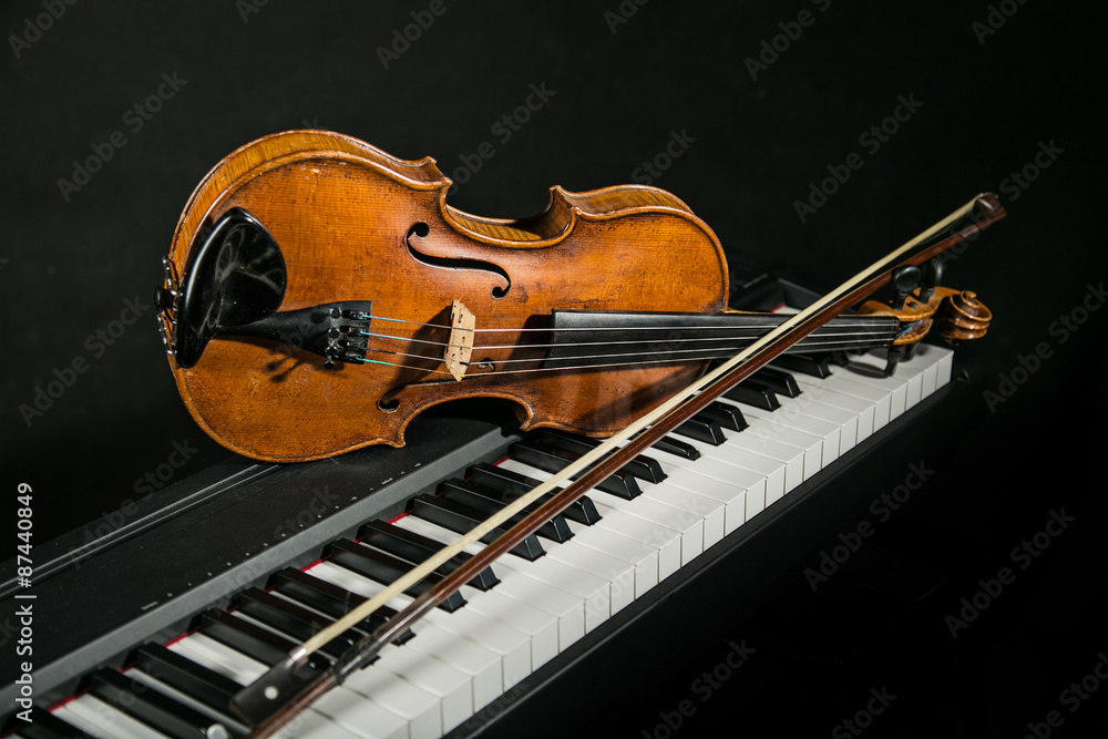 Fototapeta premium Piano keyboards with old violin on dark background.