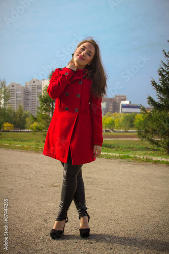 Beautiful girl in a red coat on a park alley