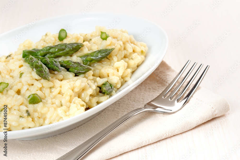 plate of risotto with asparagus over a napkin and fork plate of risotto with asparagus over a napkin and fork