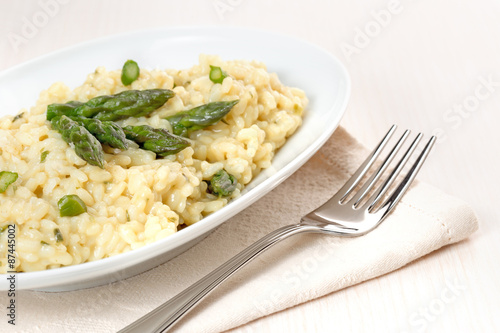 plate of risotto with asparagus over a napkin and fork