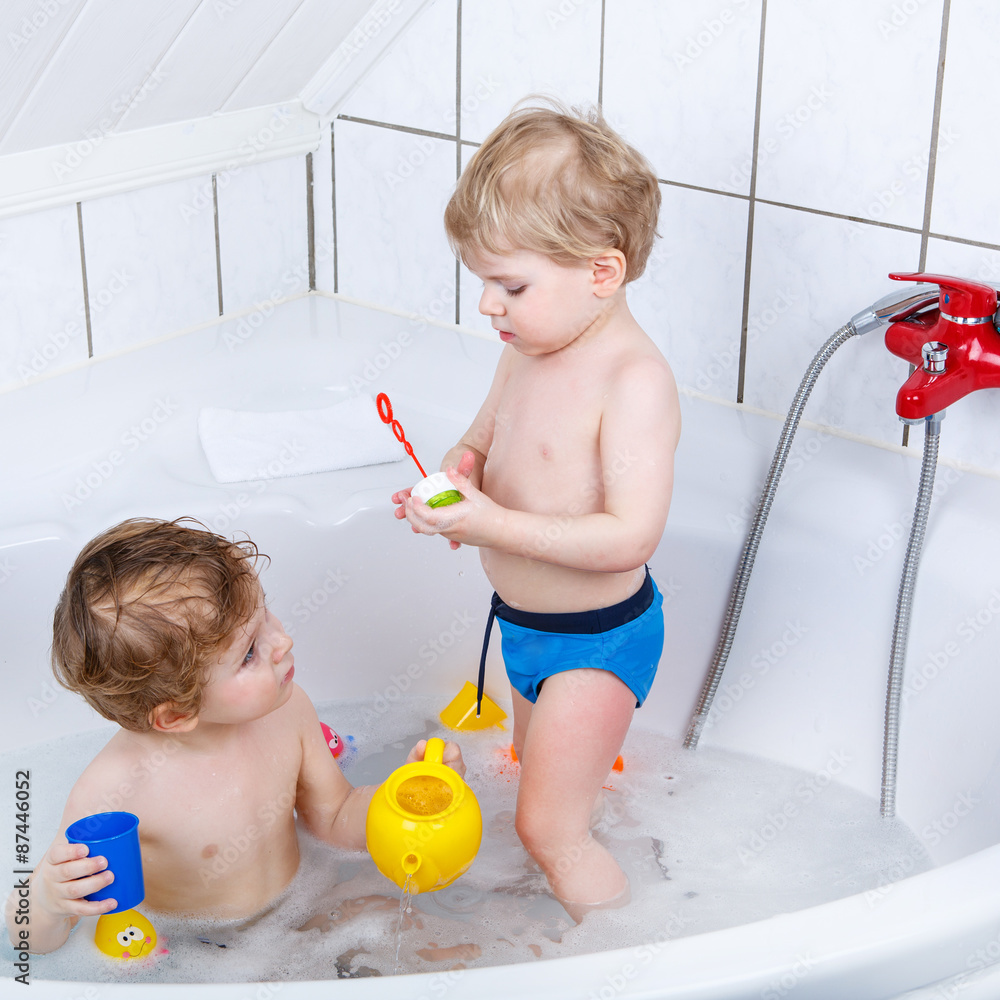 Two little sibling boys having fun with water by taking bath in Two little sibling boys having fun with water by taking bath in