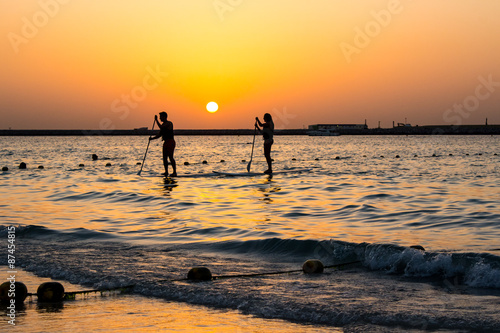 A couple surfers at sunset