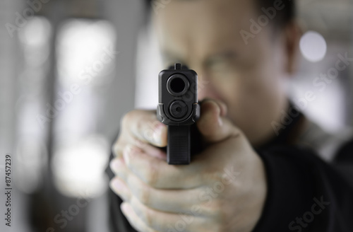 A man aims his semi automatic pistol. Selectively focused on the
