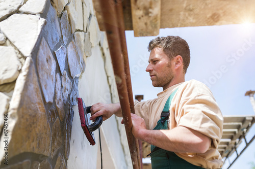 Man putting natural stones on a wall