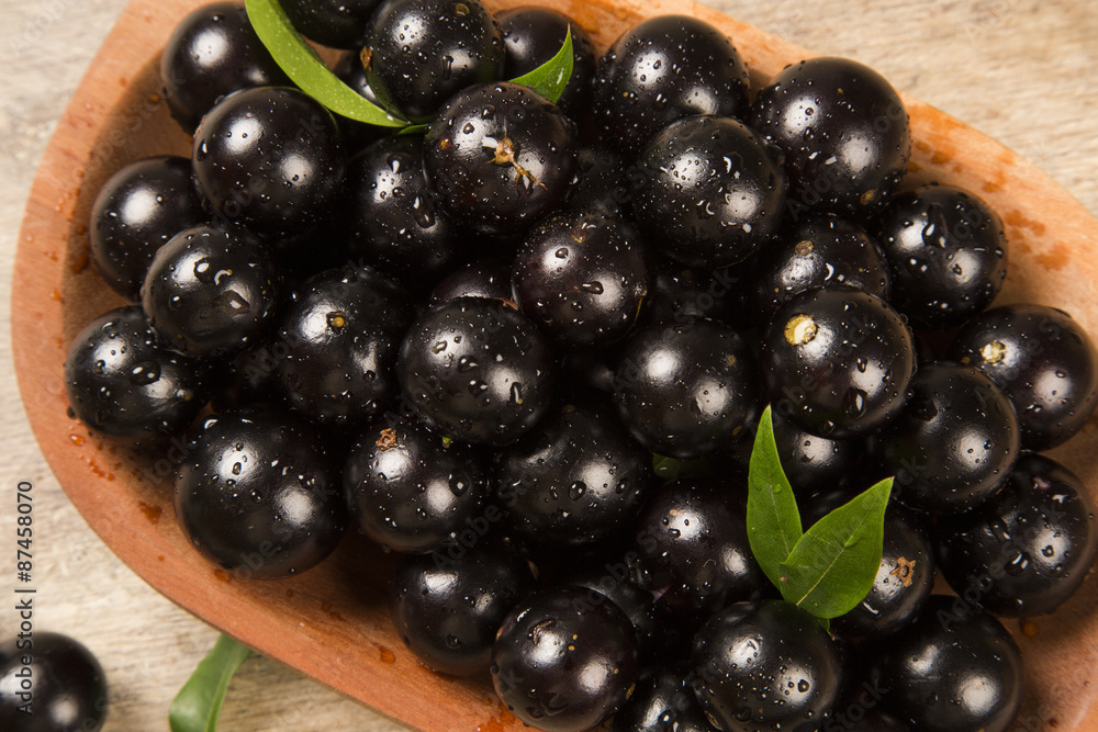 Berry Jaboticaba in bowl on wooden table Berry Jaboticaba in bowl on wooden table