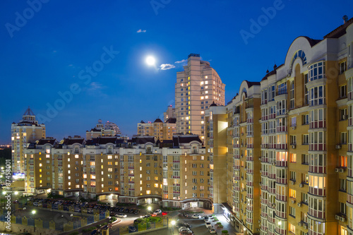 Moon in the night sky over city. © Roman Rvachov