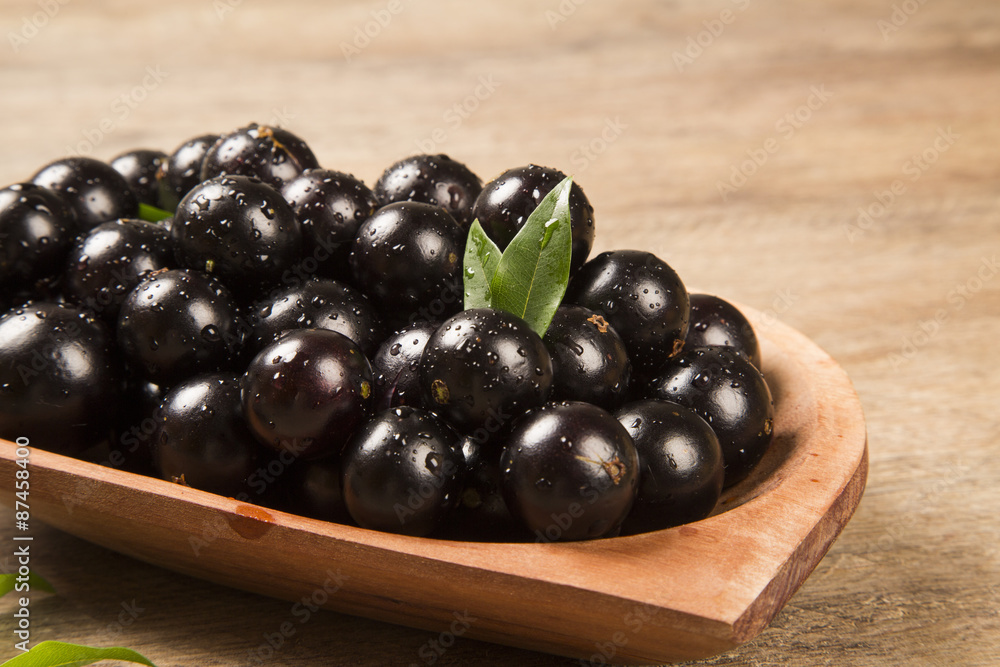 Berry Jaboticaba in bowl on wooden table Berry Jaboticaba in bowl on wooden table