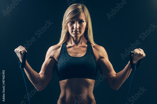 Fotografie Athletic young woman working on biceps with expander