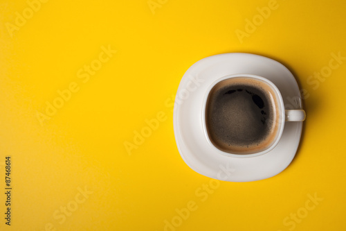 cup of fresh espresso on yellow background, view from above