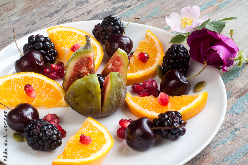 Healthy breakfast of fresh fruit including fig, sliced orange, blackberries, cherries and pomegranate seeds. Served on a rustic wooden table with fresh wild flowers. Healthy breakfast of fresh fruit including fig, sliced orange, blackberries, cherries and pomegranate seeds. Served on a rustic wooden table with fresh wild flowers.