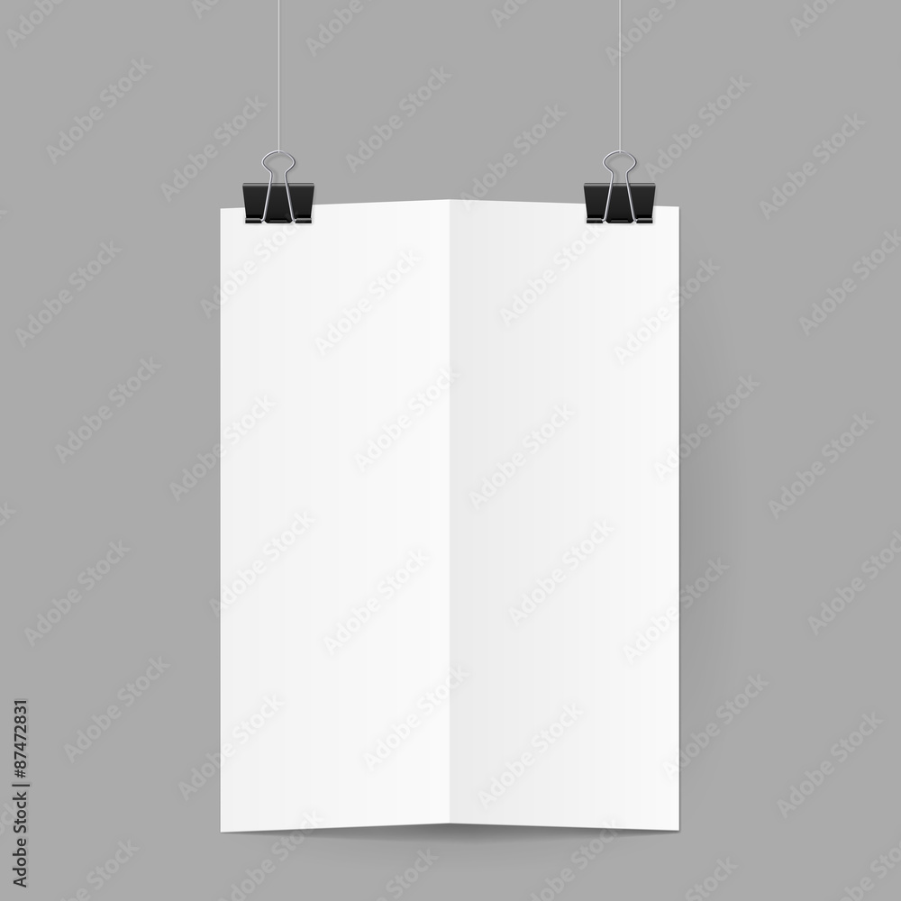 White sheet of paper folded in half handing on black binder clips White sheet of paper folded in half handing on black binder clips