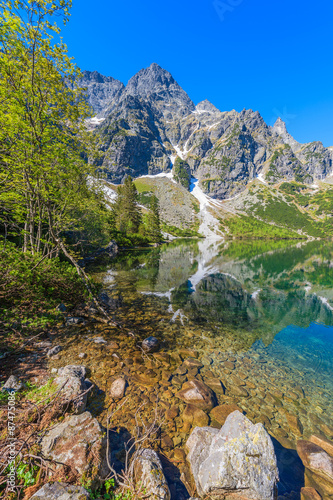 Reflection of mountain peaks in beautiful green water Morskie Oko lake, Tatra Mountains, Poland