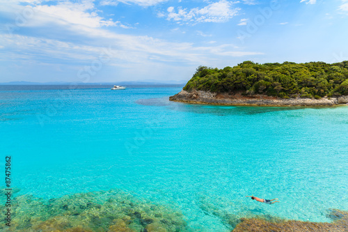 Man snorkeling in turquoise sea water of Petit Sperone bay, Corsica island, France