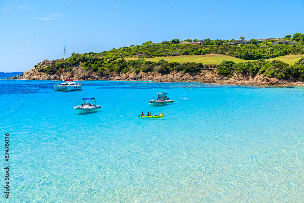 Boats and kayak on turquoise sea water of Grande Sperone bay, Corsica island, France.