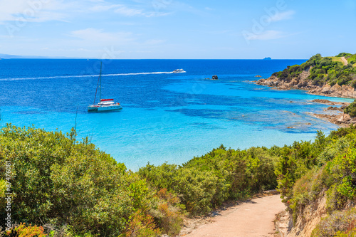 Path to Grande Sperone beach with catamaran boat on sea in distance  Corsica island  France