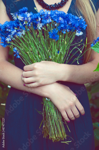 Woman in blue dress holding a bouquet of cornflowers