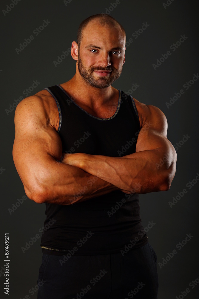 Portrait of muscular man in black shirt standing on gray background Portrait of muscular man in black shirt standing on gray background