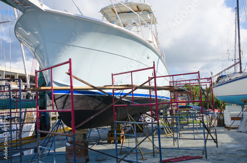 Boatyard repair big powerboat on racks surrounded with work scaffolding
