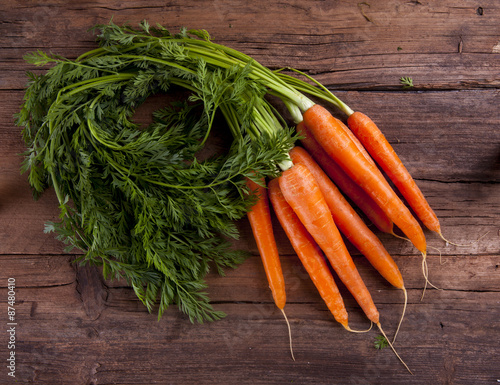 Carrots bunch with leaves shot from above on a wooden background 