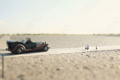 four travelers(miniature) and a classic car on country road.Shallow depth of field composition and soft pastel style.