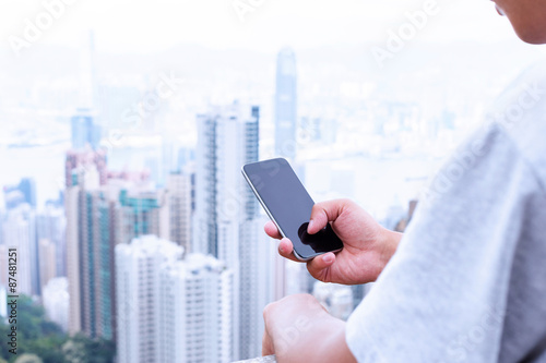 hand holding mobile phone with cityscape as background