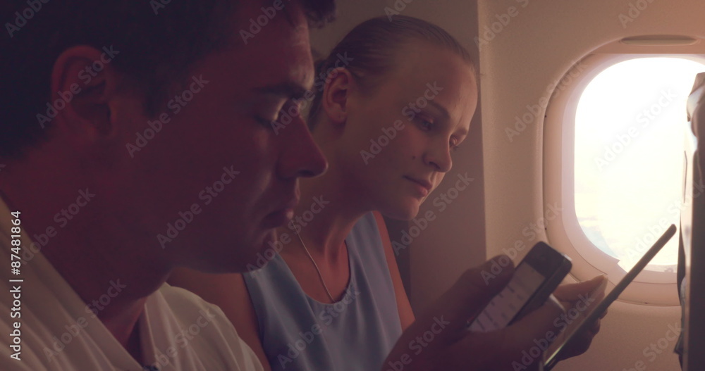 Young people using tablet PC and cell phone in plane