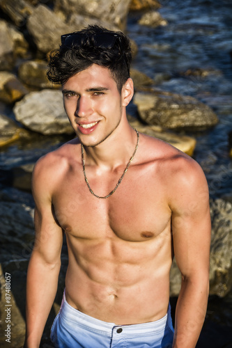 Muscular young man shirtless at sea