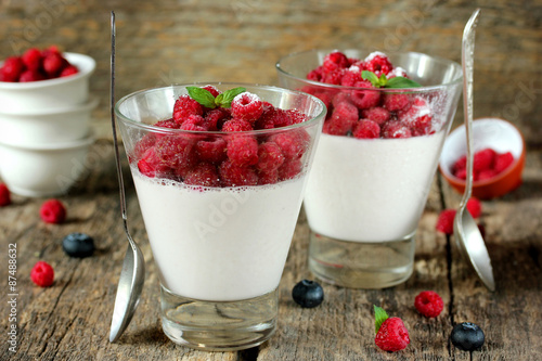 Italian panna cotta with raspberries in a glass on a wooden tabl