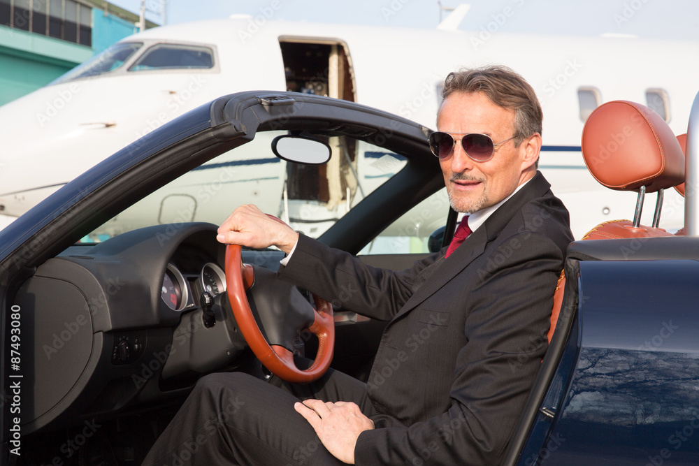 executive business man in a cabriolet in front of corporate priv