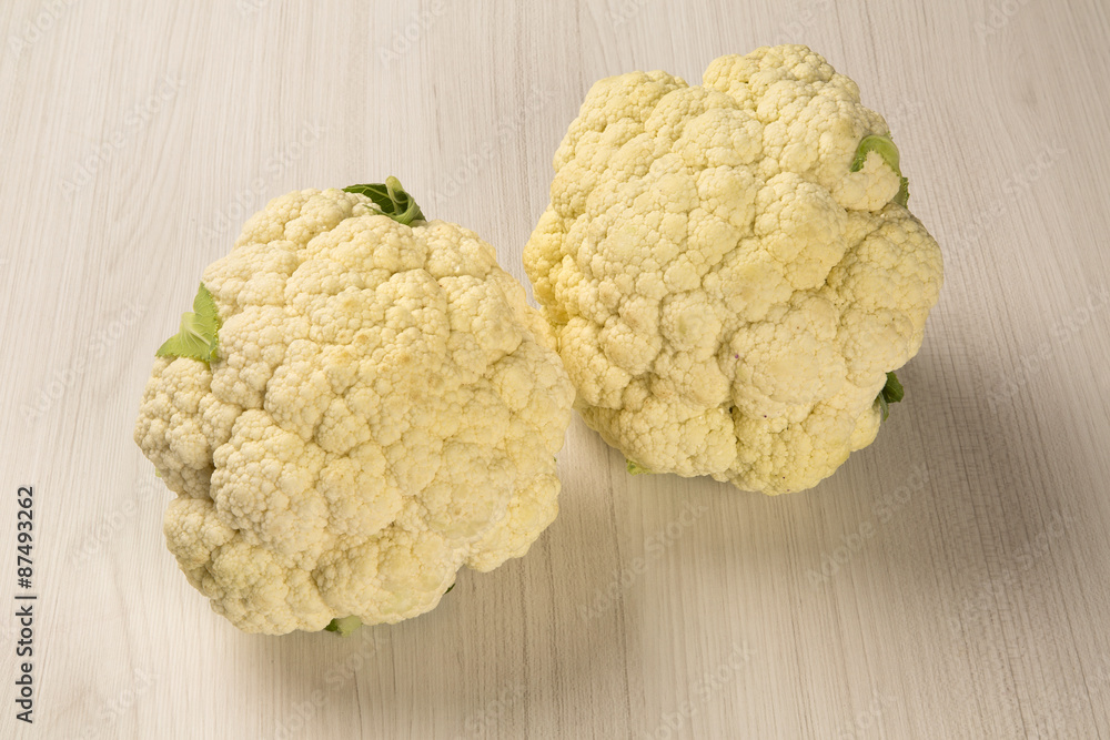 Some white cauliflowers over a wooden surface seen from above Some white cauliflowers over a wooden surface seen from above