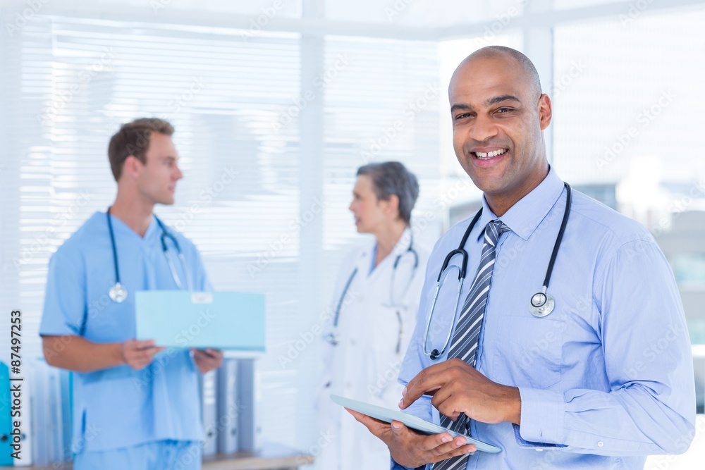 Smiling doctor using his tablet Smiling doctor using his tablet