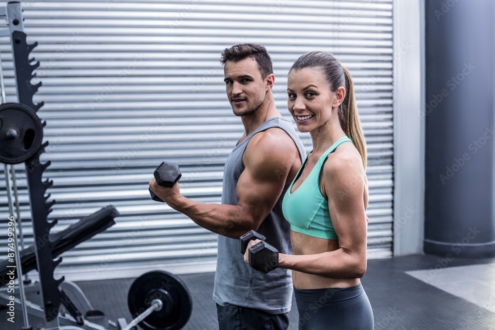 A muscular couple lifting dumbbells A muscular couple lifting dumbbells