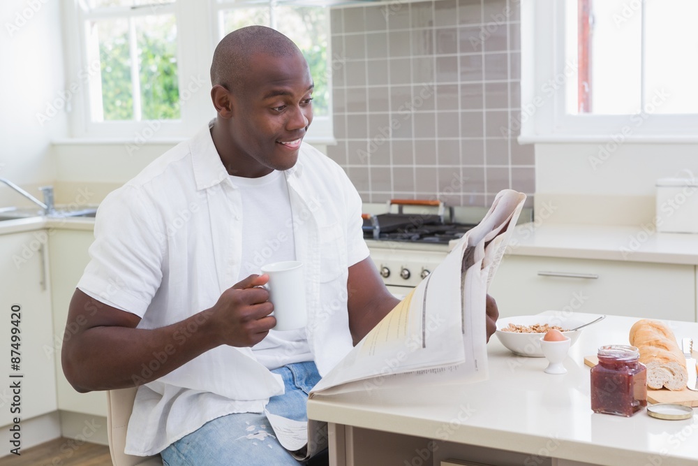 Smiling man reading a newspaper and drinking tea Smiling man reading a newspaper and drinking tea
