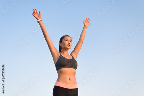 Asian woman raising arms to the sky.
