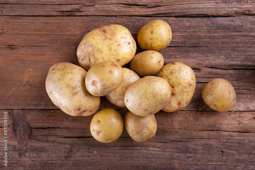 Potatoes bunch shot on a wooden background from above Potatoes bunch shot on a wooden background from above